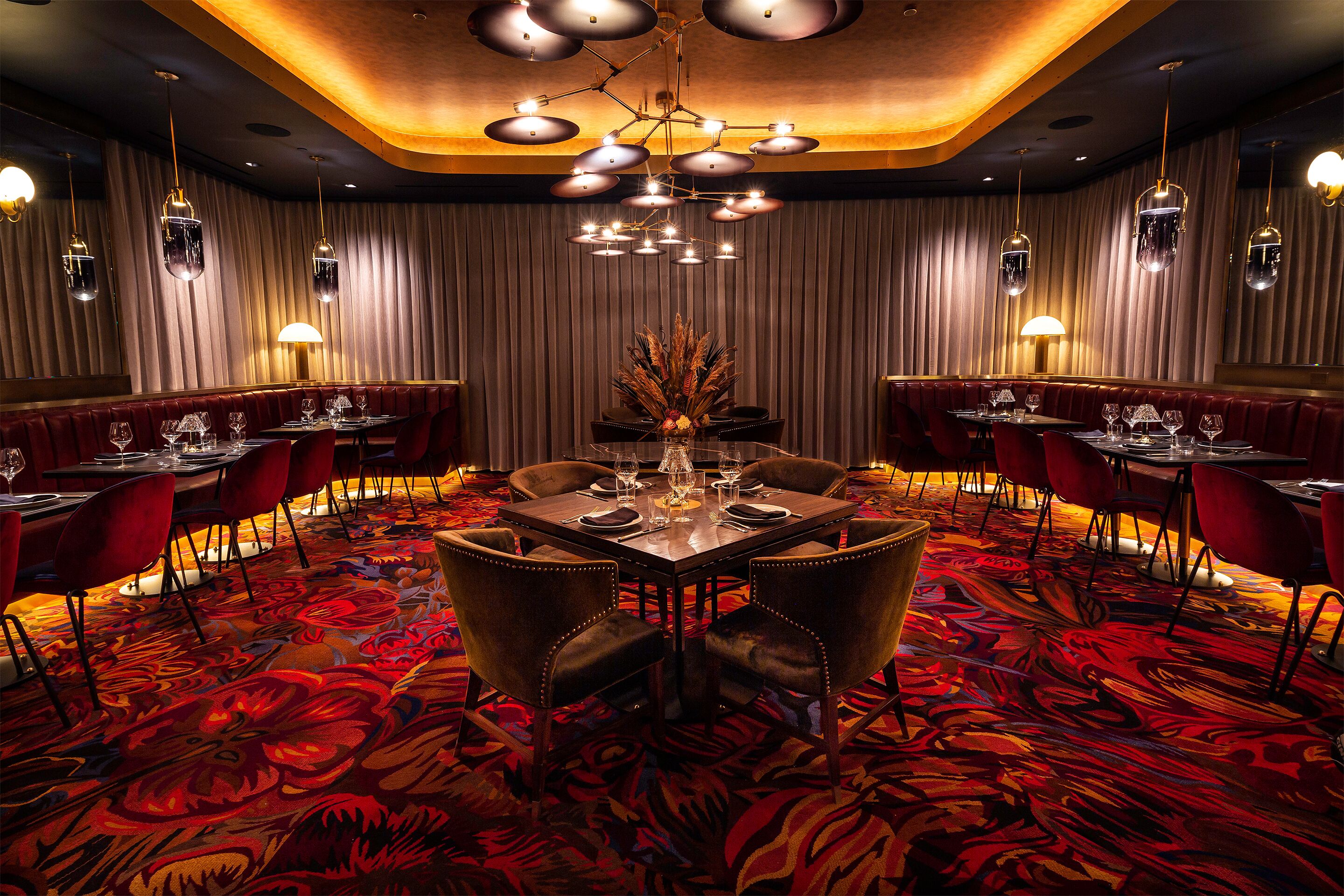A restaurant with a red carpet, multiple tables, and chairs.