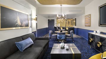 Un hall d’hôtel moderne avec un canapé bleu foncé, une table basse ronde et un coin repas comprenant des chaises et une table.