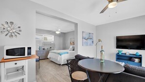 Un salon moderne avec une table ronde, un canapé, un téléviseur et un ventilateur de plafond.