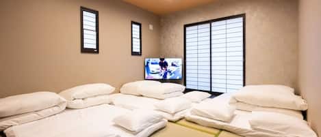 Experience the serene ambiance of a traditional Japanese-inspired room, featuring a tatami mat floor, a comfortable bed, and a large window with a grid pattern.