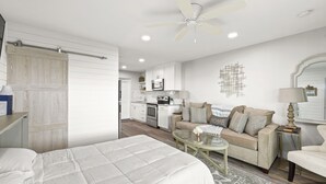 Una camera da letto con un letto grande, un tavolino in vetro, un divano e una ventola a soffitto.
