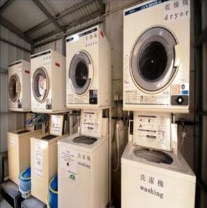Industrial-style washing machines line a functional space, equipped with front-loading drums and control panels for heavy-duty use.