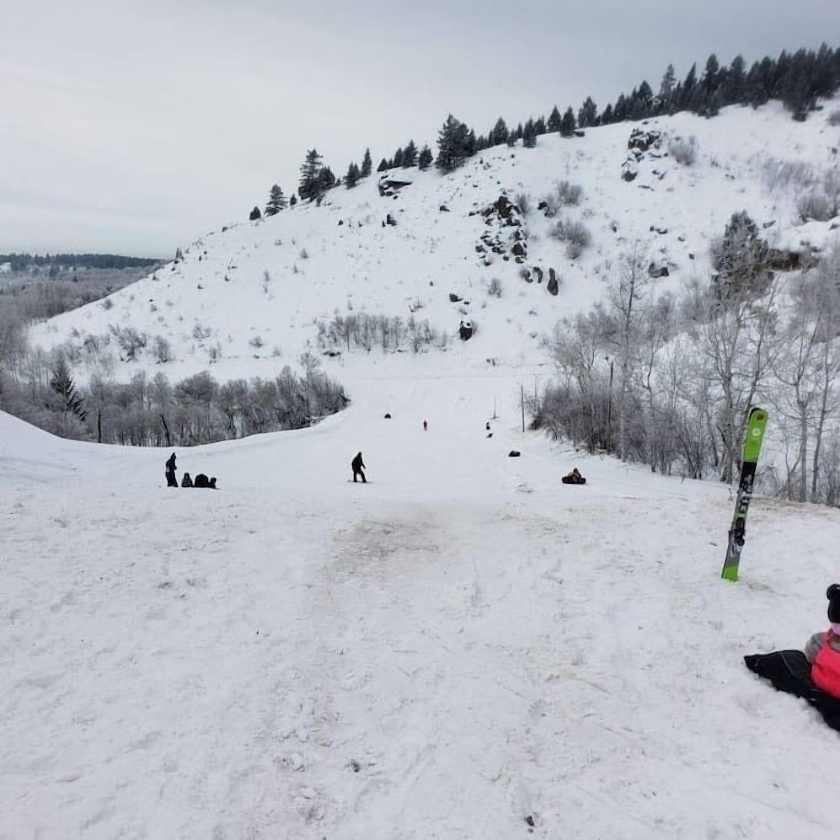 A snowy ski slope with skiers and snowboarders.
