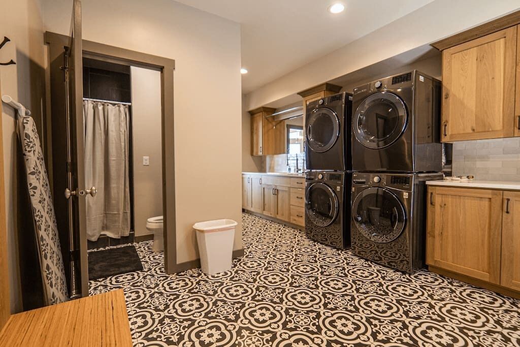 A compact kitchen with a patterned floor, wooden cabinets, and a built-in washer and dryer.