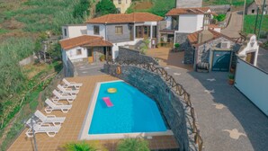 Une propriété résidentielle dotée d’une piscine, de chaises longues et d’un mur en pierre.