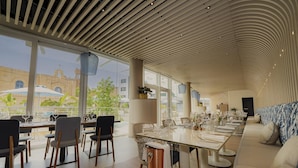 A modern dining area with a long table, chairs, and a sofa.