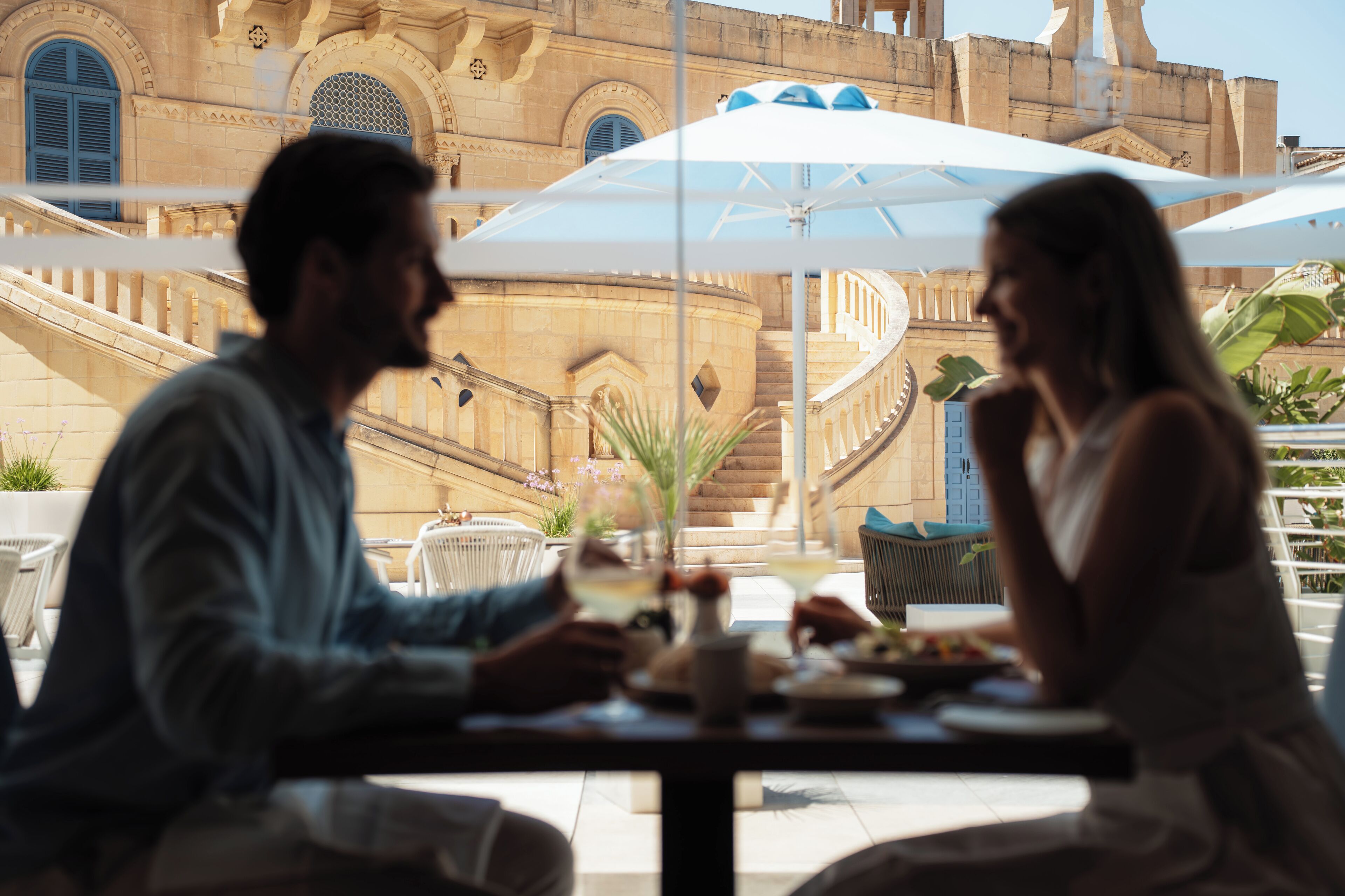 A couple dining at an outdoor table with a view of a historic building.