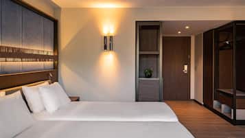 Una habitación de hotel moderna con una cama grande, una lámpara de pared, un armario de madera y una planta pequeña en un estante.