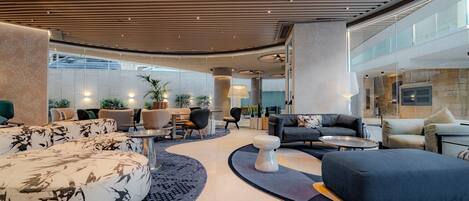 A modern lobby with a curved ceiling, seating areas, and a view of the building's interior.
