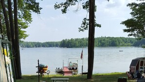 Ein Betonweg führt zu einem Steg an einem See, in der Nähe befinden sich ein Picknicktisch und Stühle.
