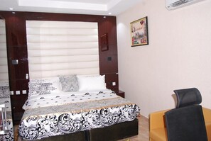 A bedroom with a large bed, a desk, and a chair. - Exclusive Serene Hotel (Enugu)