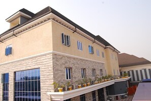 A multi-story building with a beige facade, large windows, and a balcony with potted plants. - Exclusive Serene Hotel (Enugu)