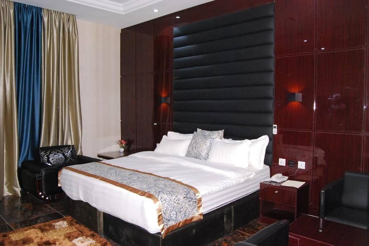 A hotel room with a large bed, a nightstand, a chair, and a desk.