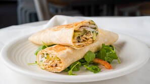 A burrito on a white plate with green salad leaves. - Exclusive Serene Hotel (Enugu)