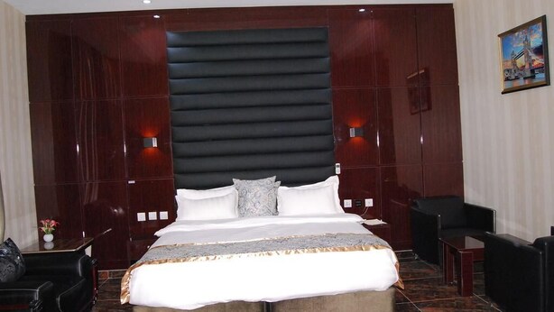 Ein Hotelzimmer mit einem großen Bett, zwei Nachttischen, einem Sessel und einem kleinen Tisch.