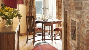 Un comedor acogedor con una mesa de madera, sillas y un jarrón de flores.