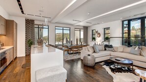 Uma sala de estar moderna com um sofá grande, uma mesa de centro e um espaço de jantar com mesa e cadeiras.