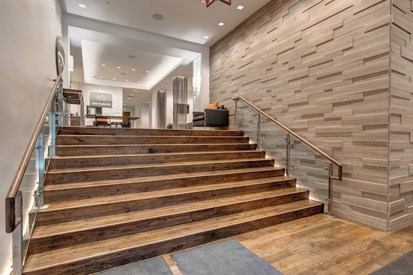 A staircase with wooden steps and metal railings, leading to a room with a modern design and a wooden wall.