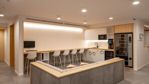 Uma cozinha moderna com uma ilha central, banquetas, uma TV de tela plana e um forno embutido.