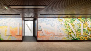 Corredor com grandes murais coloridos nas paredes e visão desimpedida da saída.
