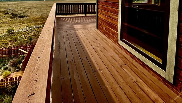 A wooden deck leading to a glass door with a view of a mountainous landscape. - The Gateway Cedar Lodge (Alma)
