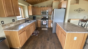 A kitchen with wooden cabinets, granite countertops, stainless steel appliances, and a wooden ceiling. - The Gateway Cedar Lodge (Alma)