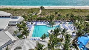 A resort with a central swimming pool, lounge areas, and a beach view. - Beach Condo in Hutchinson Island. Located in Ocean Village with Golf Course View (Hutchinson Island)