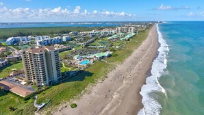 A coastal resort with multiple high-rise buildings, a sandy beach, and a view of the ocean. - Beach Condo in Hutchinson Island. Located in Ocean Village with Golf Course View (Hutchinson Island)
