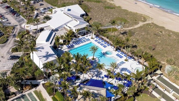 An aerial view of a resort with a large swimming pool, multiple lounge areas, and a beach. - Beach Condo in Hutchinson Island. Located in Ocean Village with Golf Course View (Hutchinson Island)