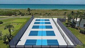 A rooftop with solar panels, a view of the ocean, and a grassy area with palm trees. - Beach Condo in Hutchinson Island. Located in Ocean Village with Golf Course View (Hutchinson Island)