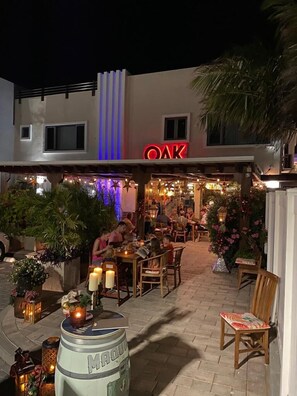 Ein Restaurant mit Außenbereich, einer Neonreklame und Zierpflanzen.