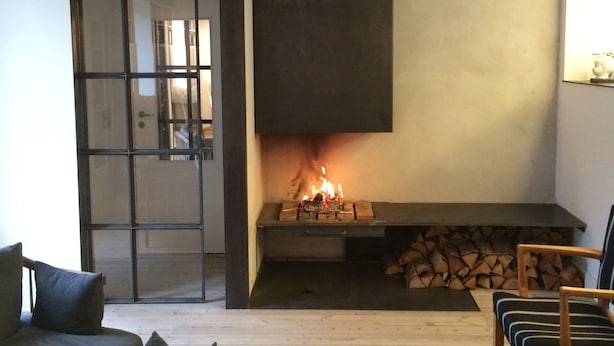 A cozy living room with a fireplace, wooden furniture, and a sliding glass door leading to another room.