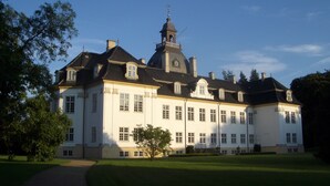 A large, stately building with a symmetrical facade, multiple windows, and a prominent tower with a clock.
