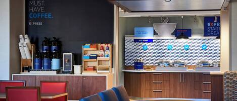 A modern cafe with a coffee station, seating area, and a counter with food options.