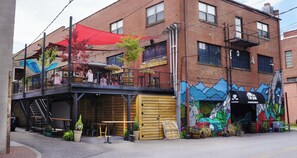 A two-story building with a ground-floor commercial space featuring outdoor seating and a mural.