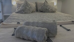 Una cama con una colcha estampada, dos almohadas y una mesita de noche.