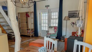 Una habitación acogedora con una mesa de comedor de madera, una silla, un sofá, una escalera y una puerta con un letrero.