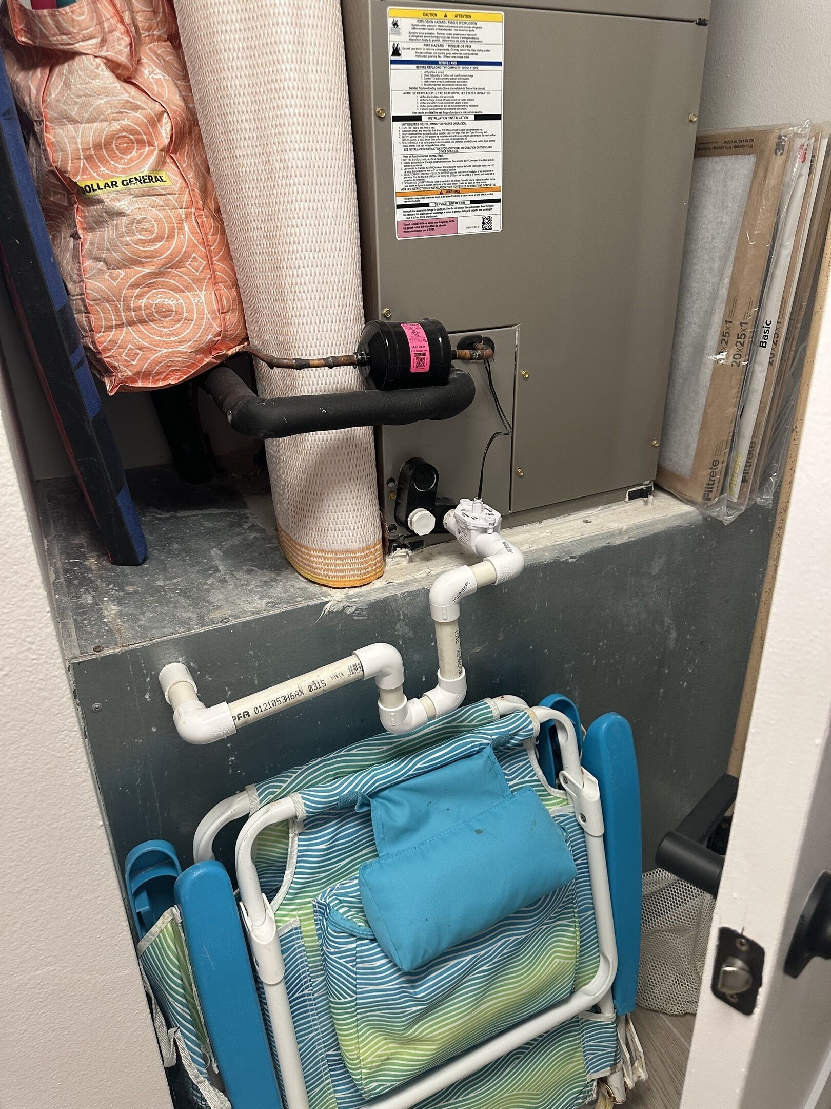 Ein Hauswirtschaftsraum mit Warmwasserbereiter, Rohren und einer Matratze.