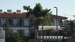 A beachfront property with a building featuring a red-tiled roof, a covered patio, and a landscaped garden.