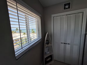 Quarto com janela vista para a praia, armário branco e decoração de parede em formato de estrela.