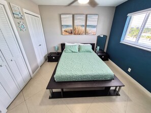 A bedroom with a bed, two nightstands, a window with blinds, and artwork on the wall. - Beautiful And Private Oceanfront Condo Directly on Hollywood Beach Boardwalk (Hollywood)