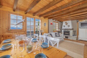 L’intérieur d’un chalet en bois, avec une table à manger dressée pour le repas, un canapé et une cheminée.