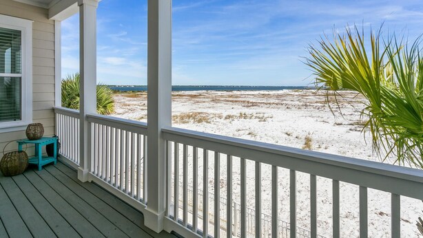Un porche cubierto con vistas a una playa arenosa y al océano.