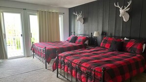 Een slaapkamer met twee bedden, een plafondventilator en decoraties van hertenkoppen aan de muur.