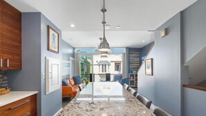 A modern kitchen with a granite countertop, wooden cabinets, and a dining area with a table and chairs. - Modern beach home only 8 houses from the beach. Check out our new drone video!! (San Diego)