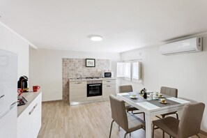 Una cocina moderna con comedor, paredes blancas y salpicadero de azulejos.