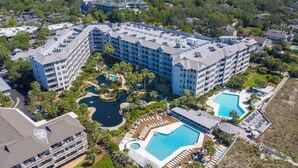 A hotel with multiple buildings, a large central pool, and smaller pools.