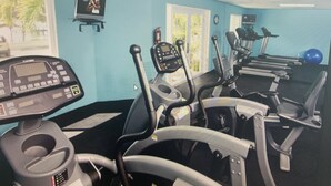 Un gimnasio con cintas de correr, elípticas y una bicicleta estática.
