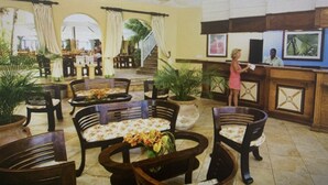 Amplio espacio interior con diversas opciones de asientos, incluyendo sillas y mesas, además de una zona de mostrador con una persona de pie.