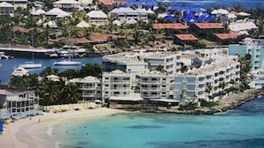 Un complejo turístico frente al mar con varias edificaciones, una playa y barcos en el agua.
